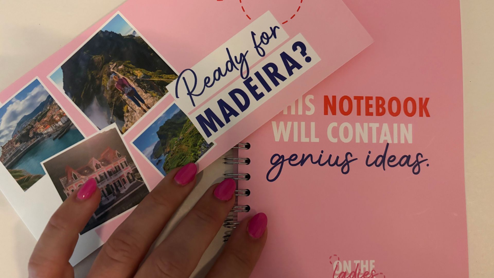 Handen met felroze nagellak houden een roze notitieboek met polaroidfoto's van Madeira en de tekst Ready for Madeira?