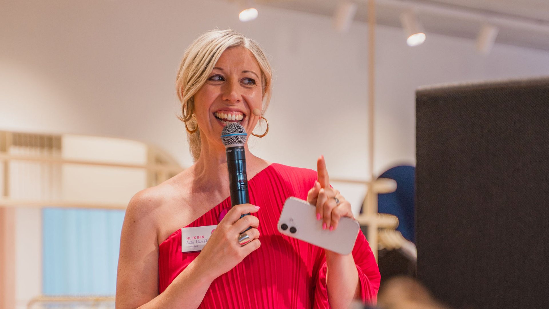 Elke Van Parys spreekt met een microfoon in de hand op het podium