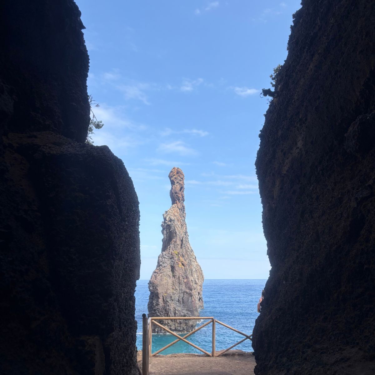Hoge rotspilaar in de oceaan, gezien tussen donkere rotsmuren op Madeira