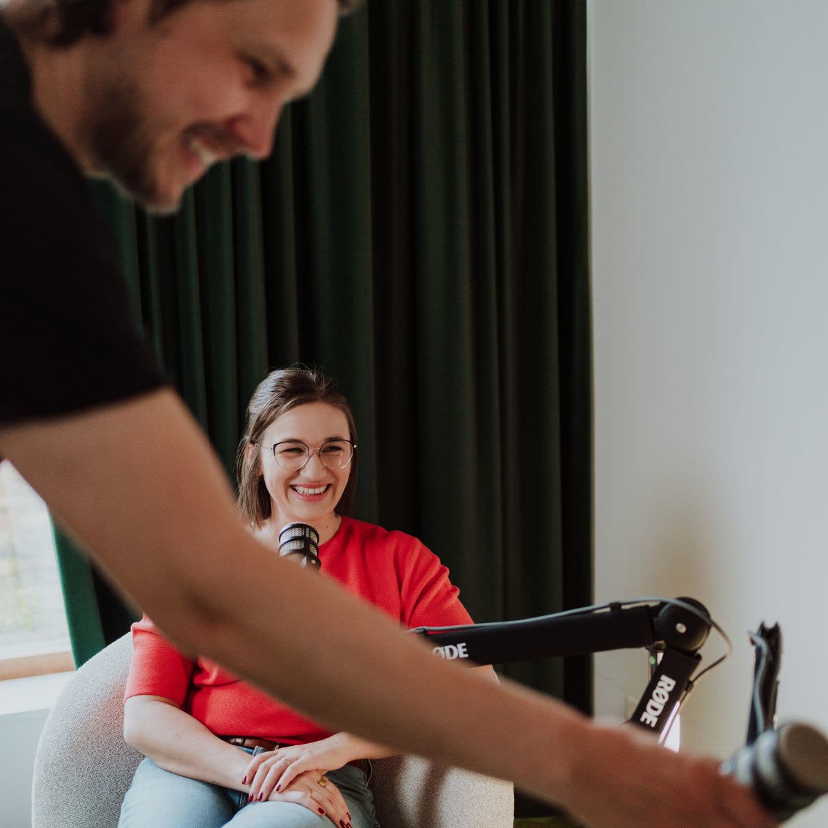 Lachende podcastgast in rood tijdens de opname