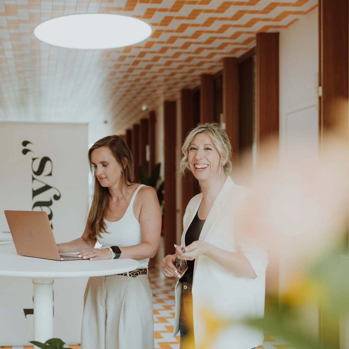 Elke Van Parys naast een collega met een laptop in de gang van heydays