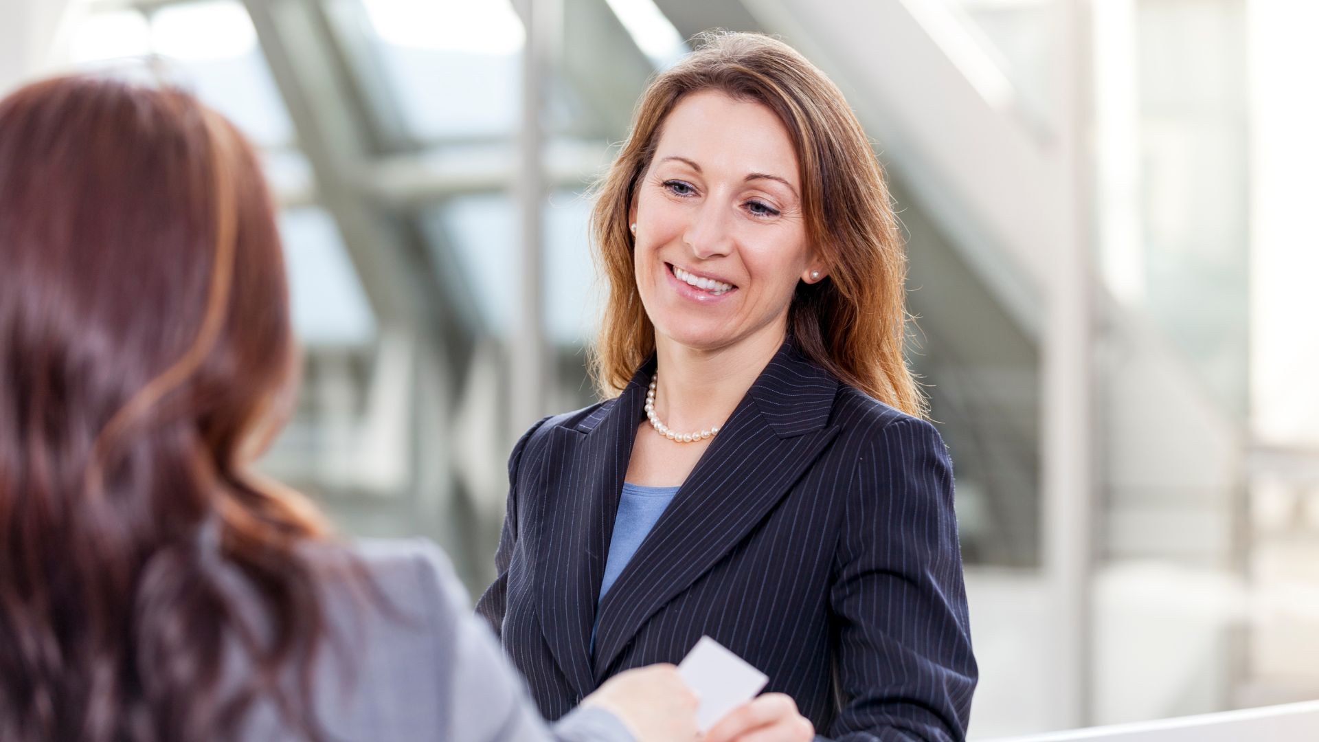 Twee professionele vrouwen in gesprek in een moderne, lichte kantooromgeving