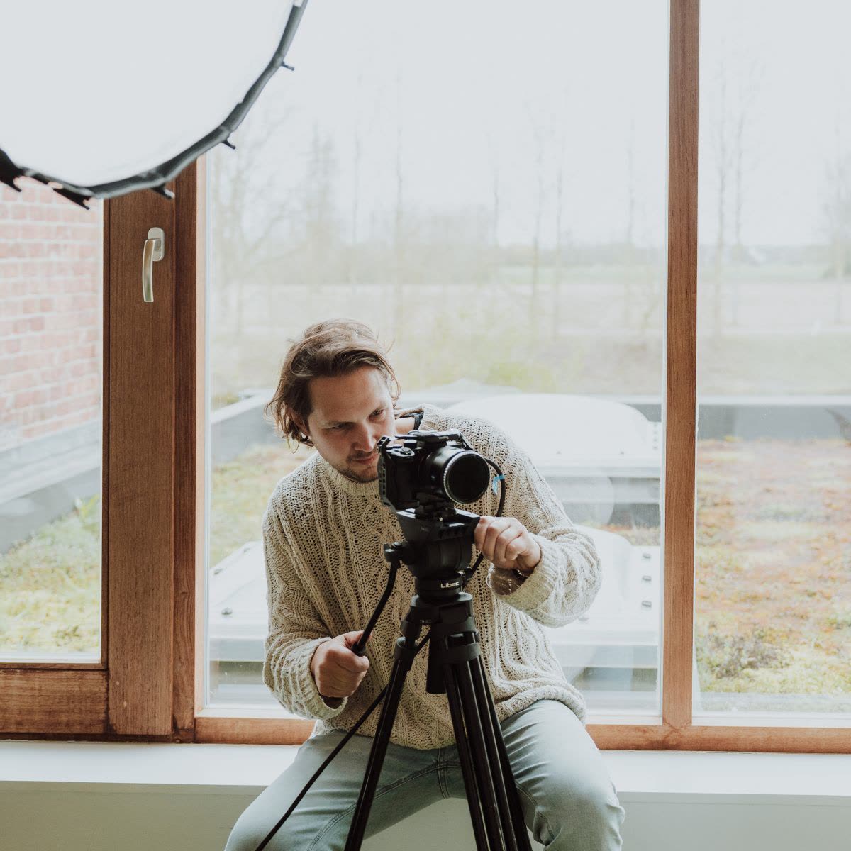 Videograaf stelt de camera in bij het raam van de studio