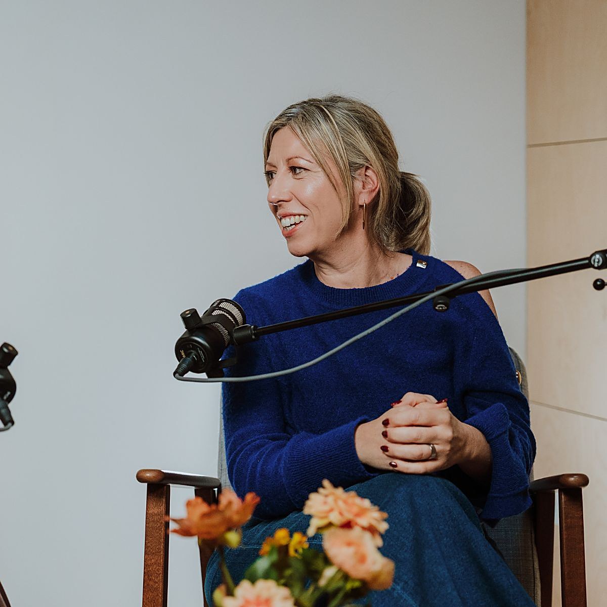 Interviewster in blauwe trui aan de microfoon in de studio