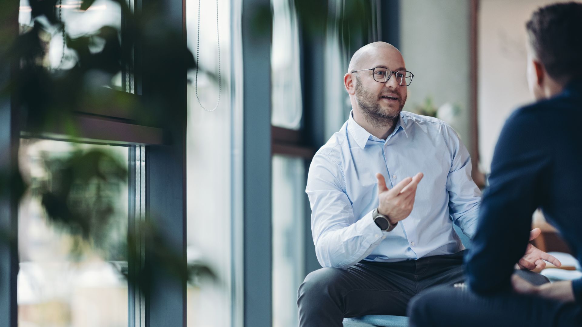 Een leidinggevende in gesprek met een collega in een lichte kantooromgeving