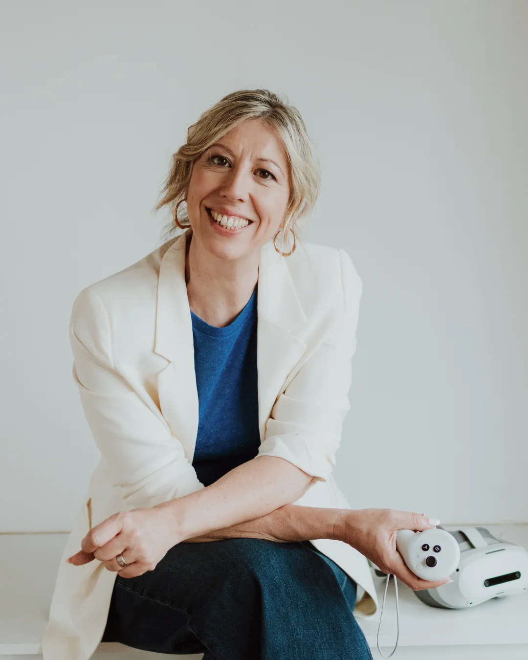 Elke Van Parys met een VR-controller in haar hand en een virtualrealitybril naast zich in de studio in Deinze