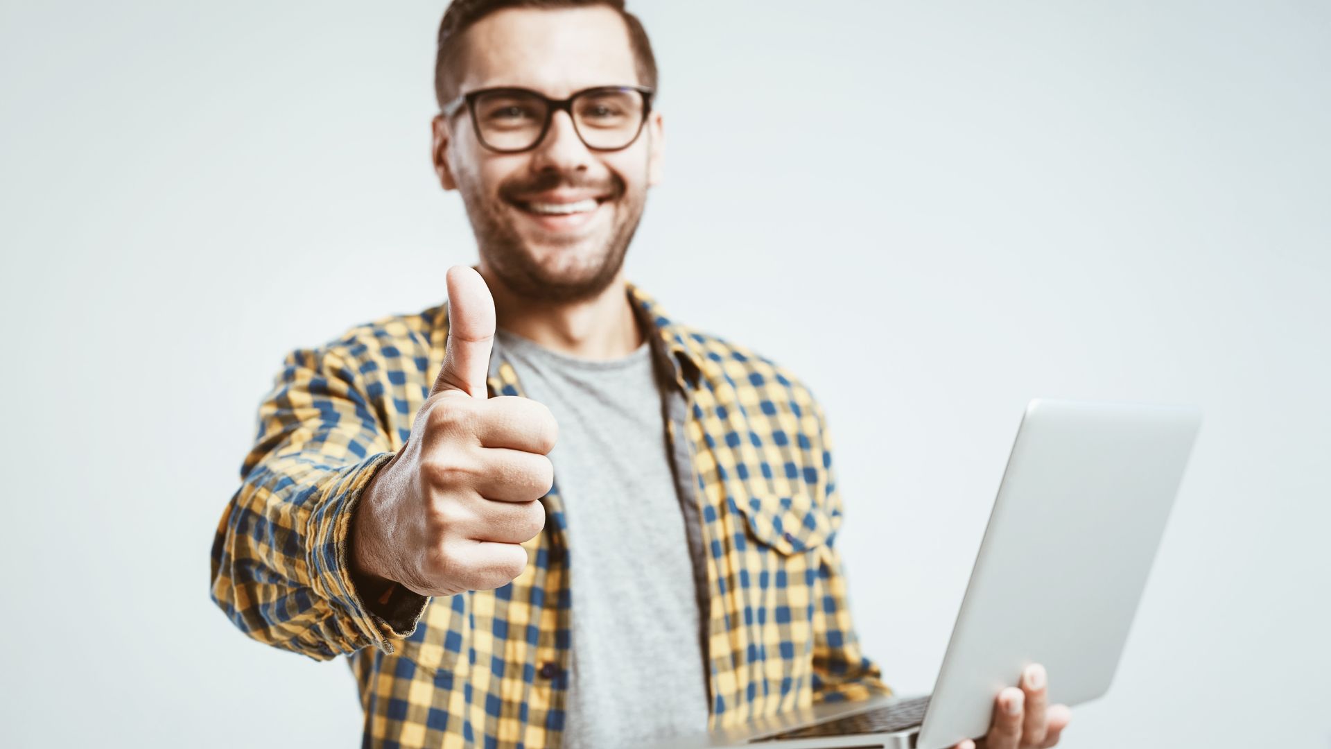Lachende medewerker met laptop die een duim omhoog steekt tijdens een taalcoaching Nederlands