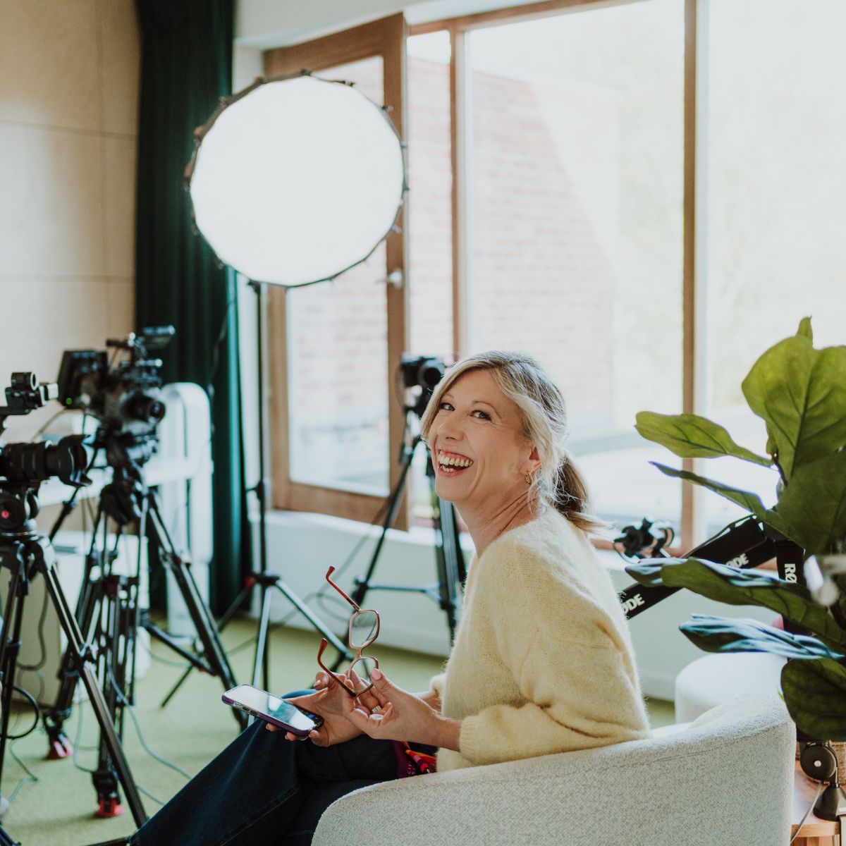 Lachende gast in de studio met softboxen en camera's